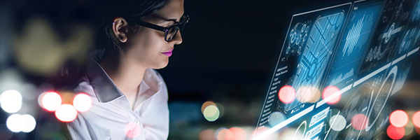 Eine IT-Frau sitzt in ihrem Büro und schaut auf sofort einsatzbereite virtuelle Dashboards für die Geräteanalyse.